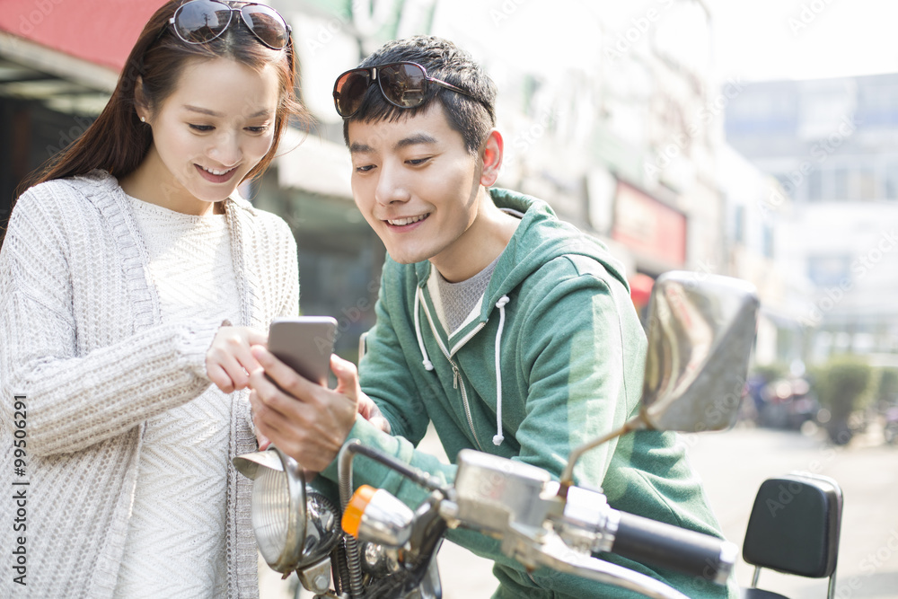 Young couple using smart phone with a motorcycle