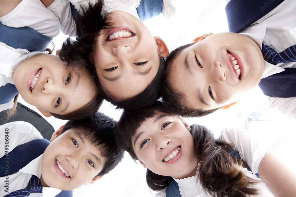 Cute schoolchildren huddling in a circle smiling happily