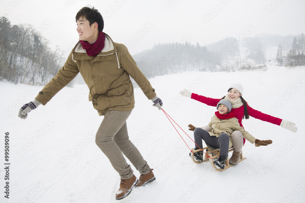 快乐的一家人在雪地上玩雪橇