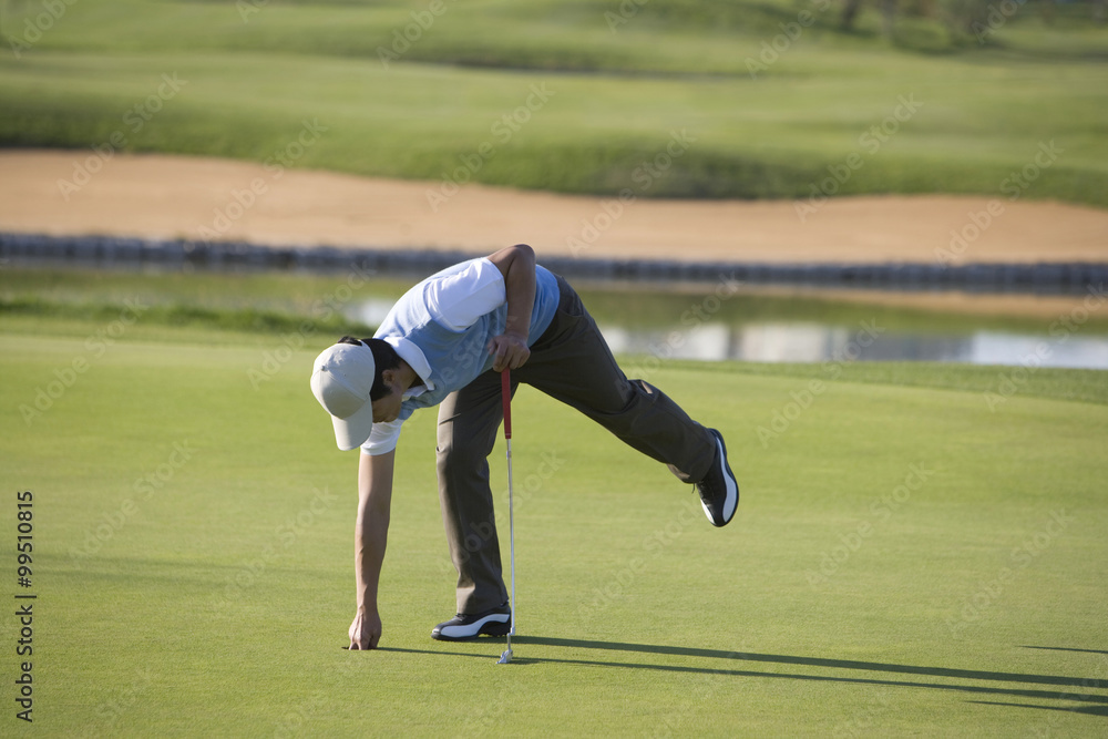 Man picking up golf ball from golf hole