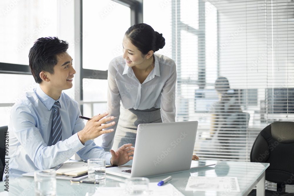 Young businesswoman and businessman talking in office