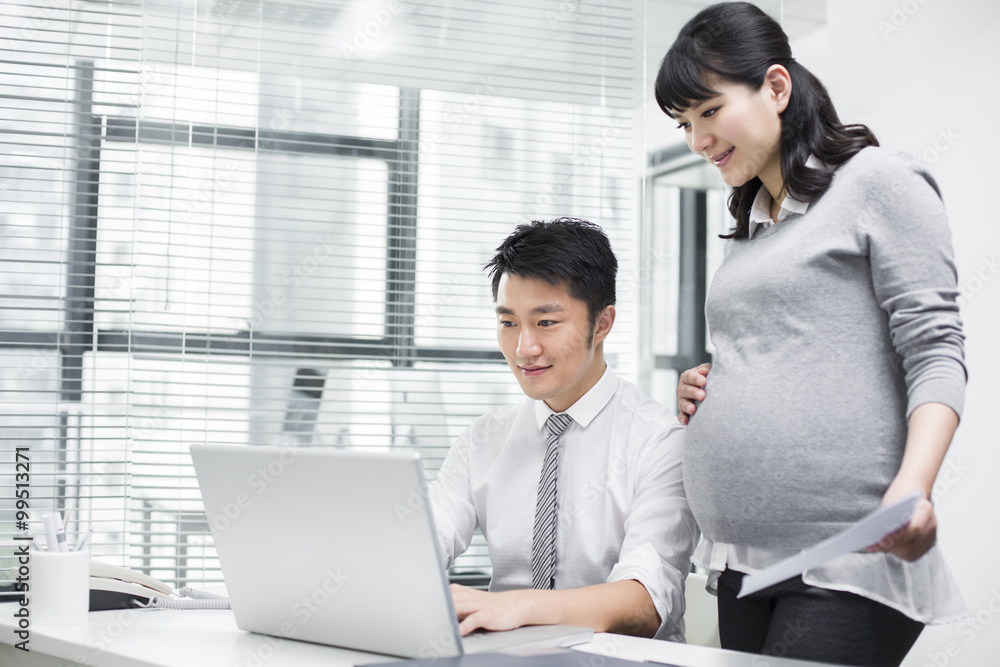 Pregnant businesswoman working with colleague