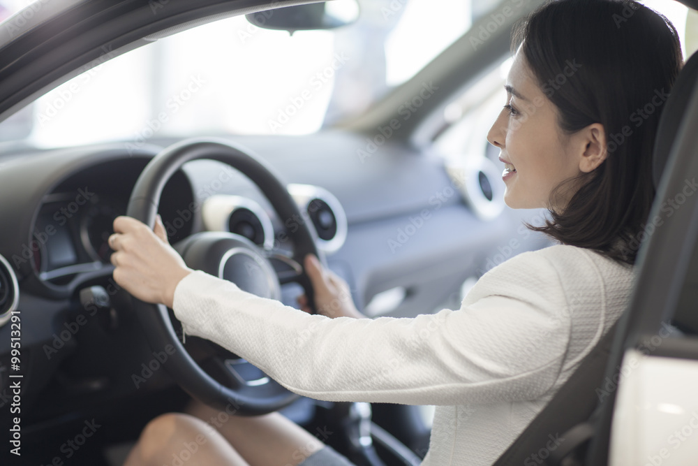 Young woman choosing car in showroom