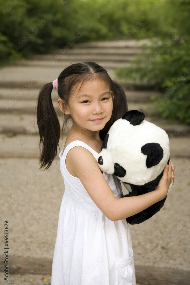 Young Girl Standing In Park Holding Panda Soft Toy