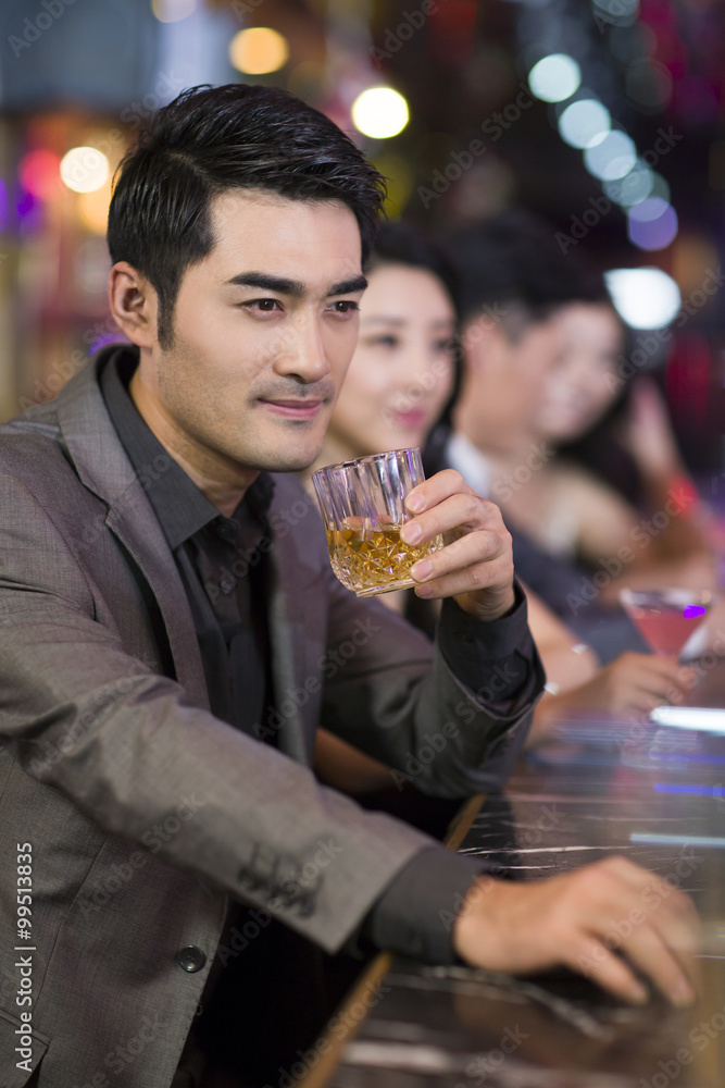 Young man drinking alcohol in bar