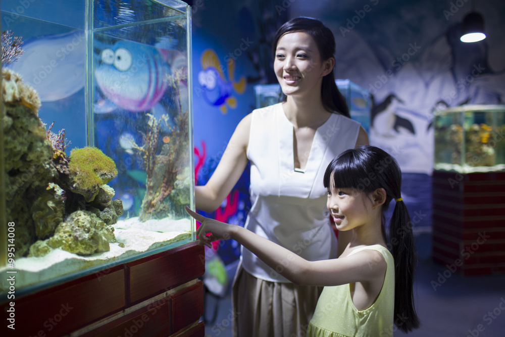 Young mother and daughter in aquarium