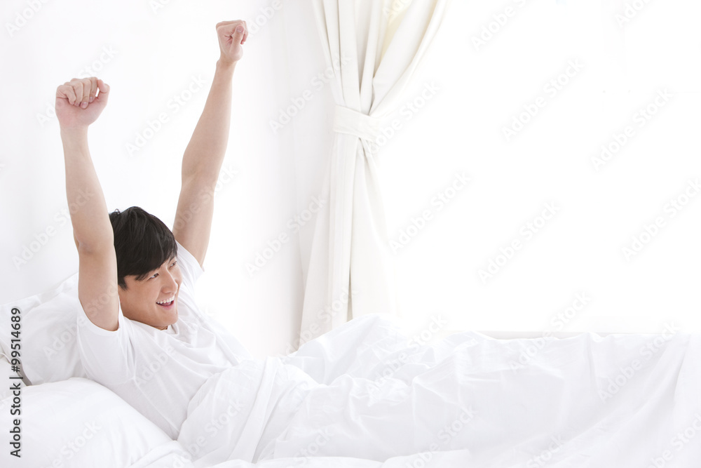 Young man giving a stretch in bed