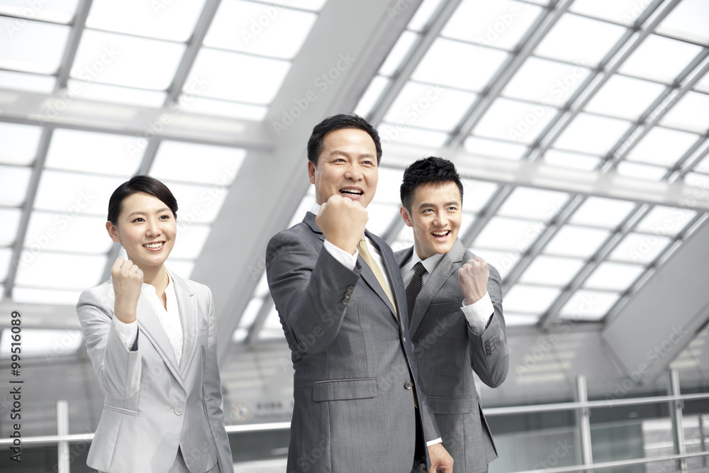 Excited business people celebrating in airport lobby