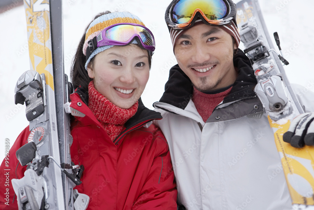 情侣站在滑雪场上，拿着滑雪