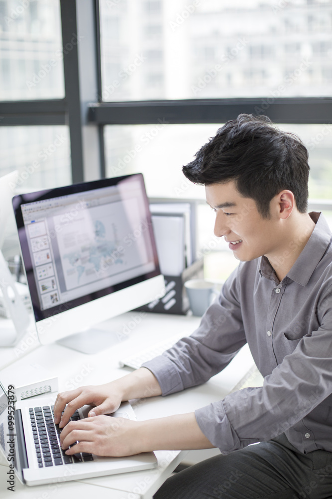 Young businessman using laptop in office