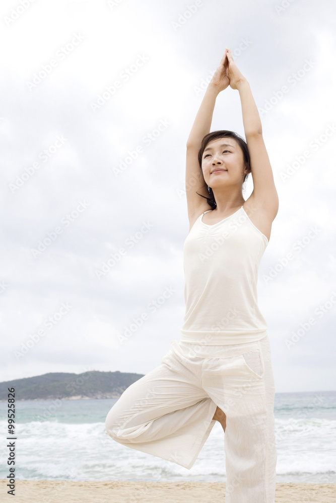 A woman practicing yoga at the beach