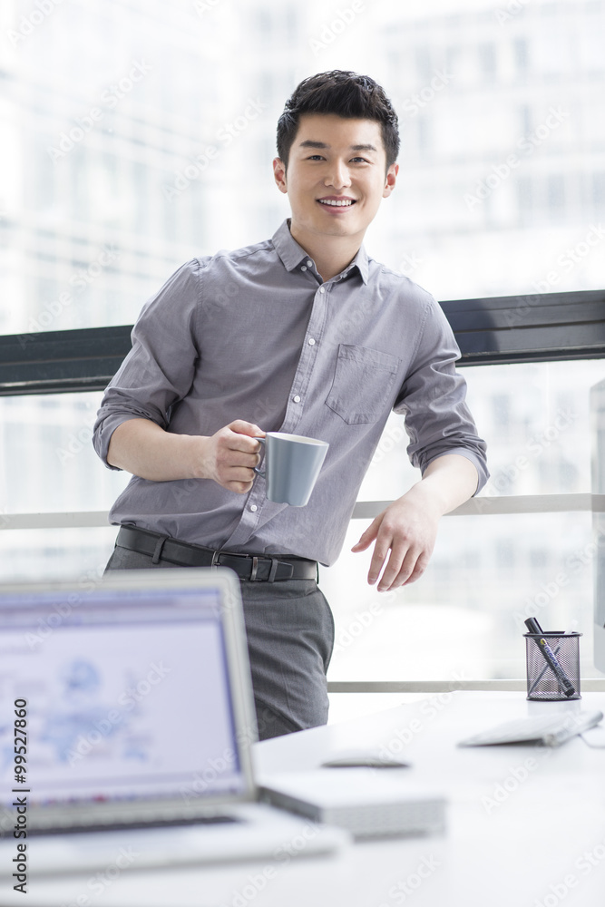 Young businessman drinking coffee in office