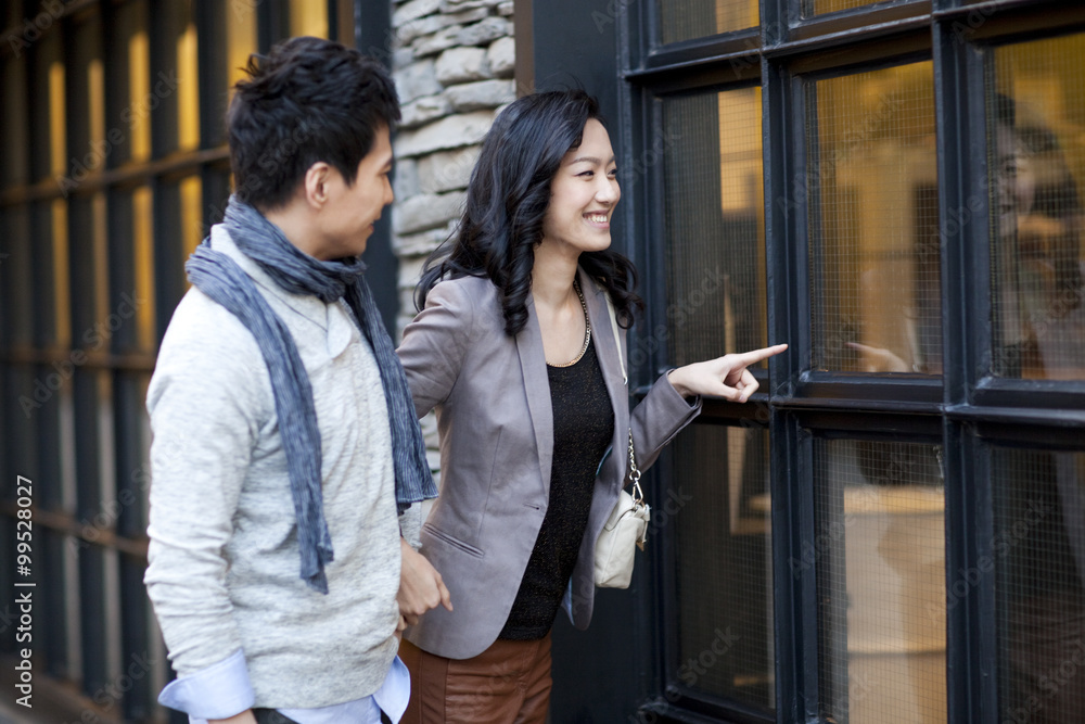 Sweet young couple doing window-shopping in city street