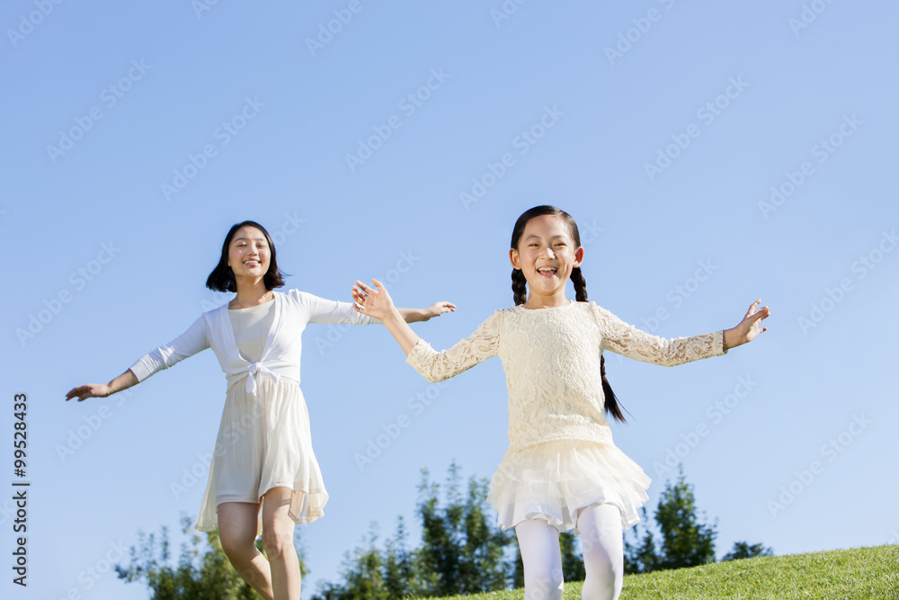 Cheerful mother and daughter playing on the lawn