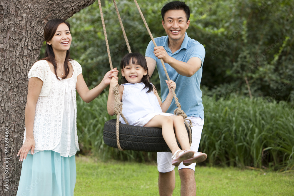 Cheerful family playing on a swing outdoors