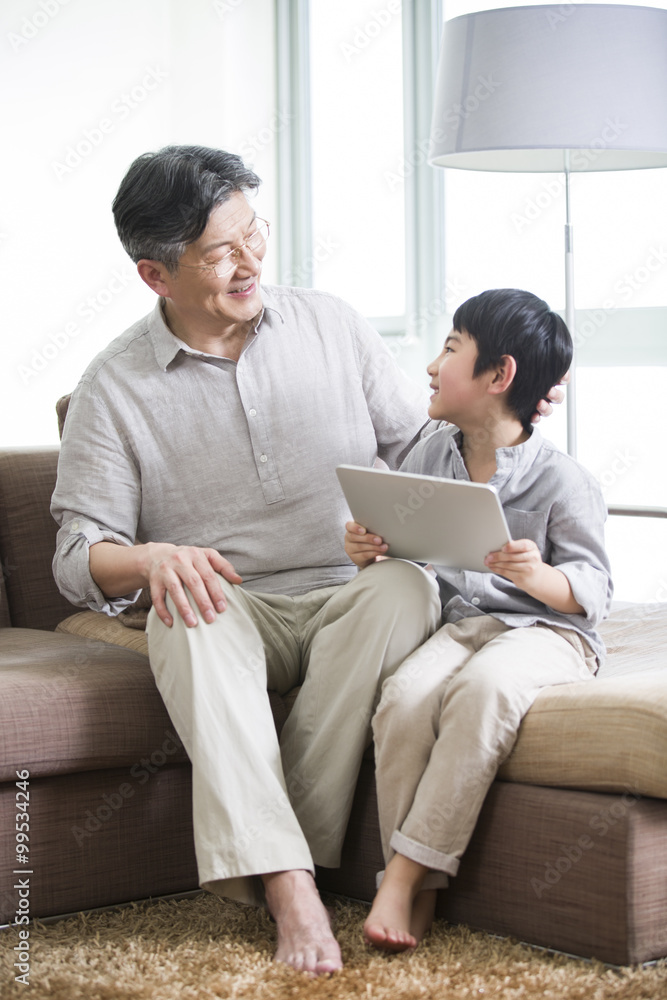 Happy grandfather and grandson with digital tablet