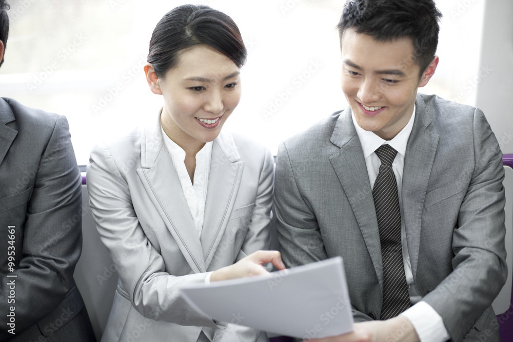 Business partners reading files in subway train