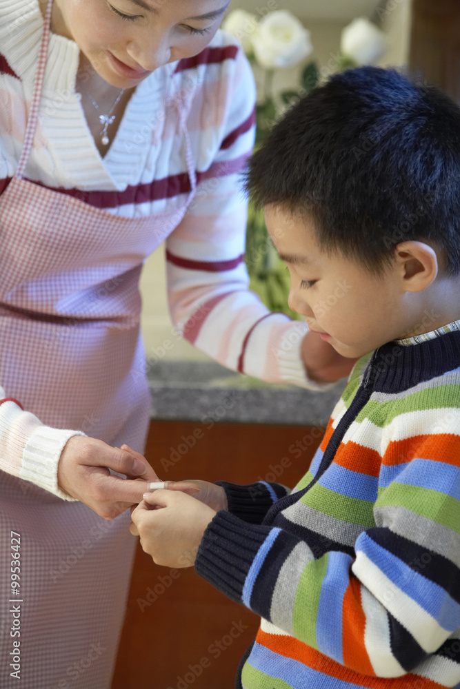 Boy Putting Band-Aid On Mothers Finger