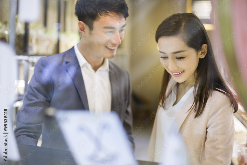 Young couple choosing cakes in bakery