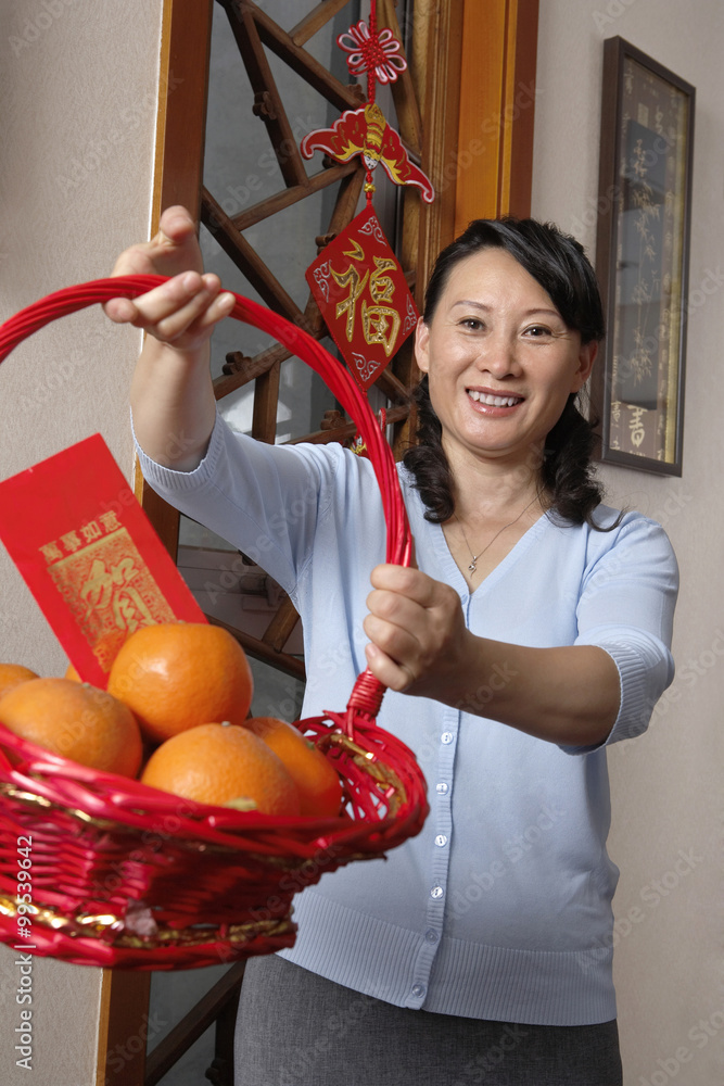 庆祝中国新年的女人捧着一篮子橙子