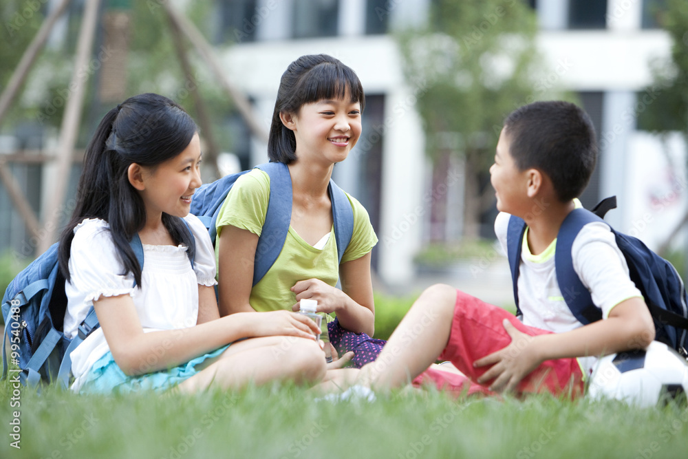 小学生坐在草坪上玩得开心