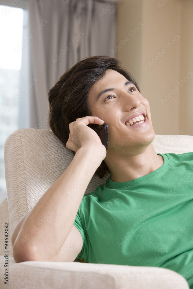 Asian man talking on the phone on a sofa