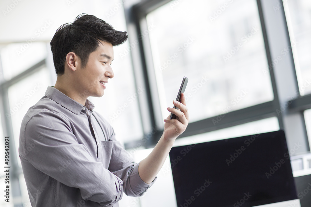 Young businessman using smart phone in office