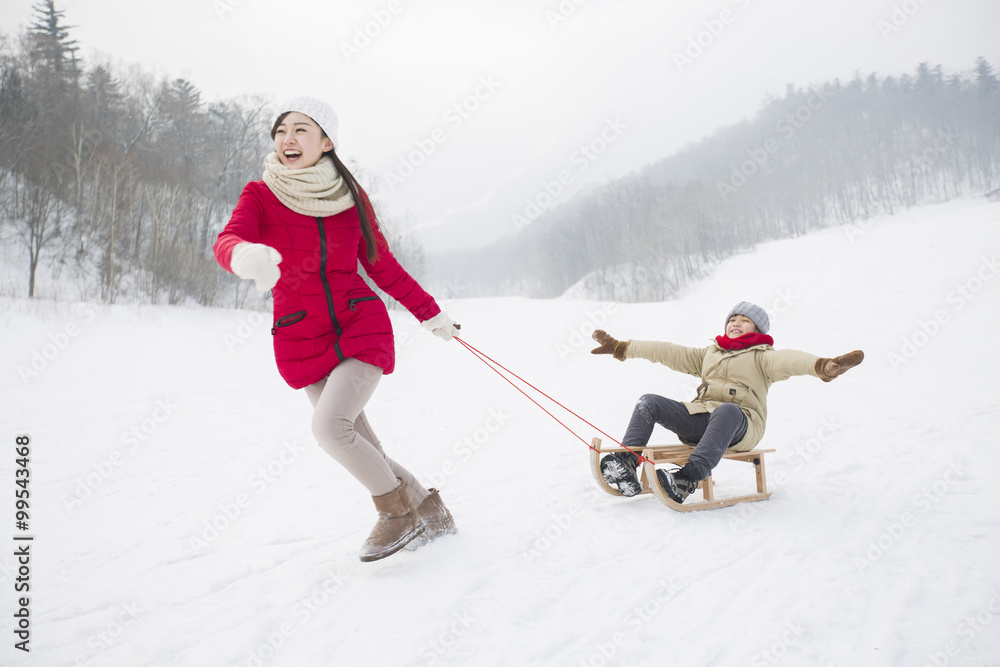 Young mother pulling son on sled