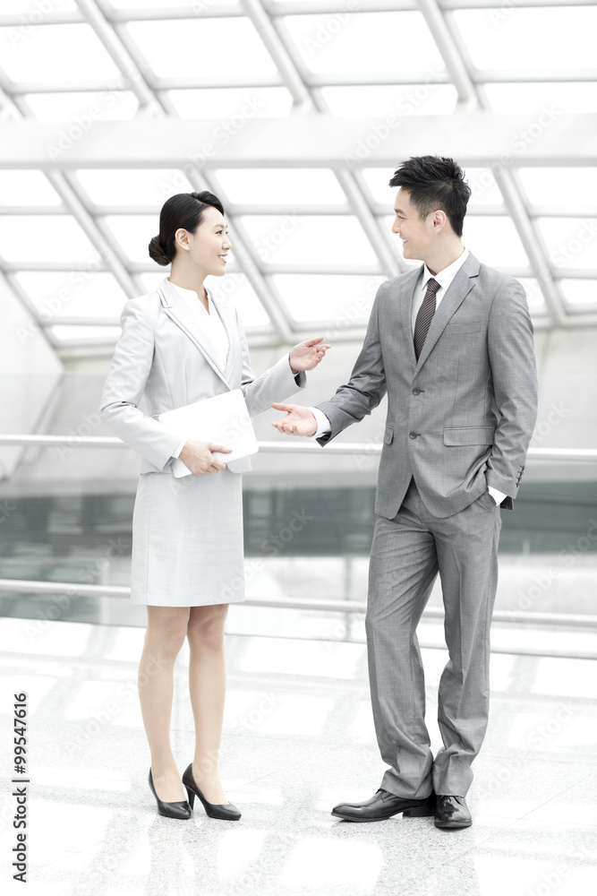 Business colleagues with digital tablet talking in airport lobby