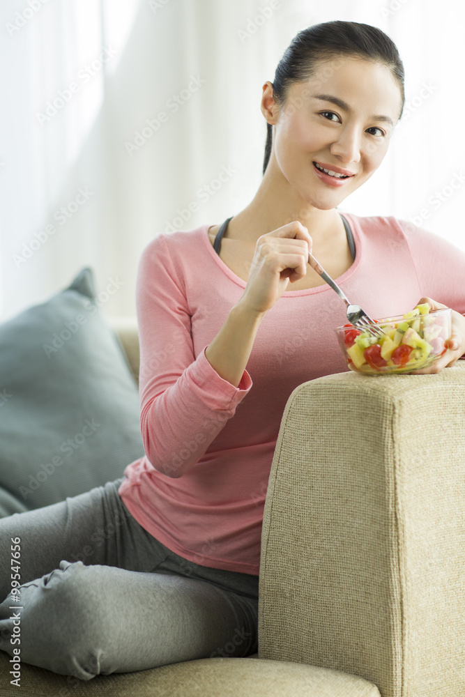 快乐的年轻女人吃水果沙拉