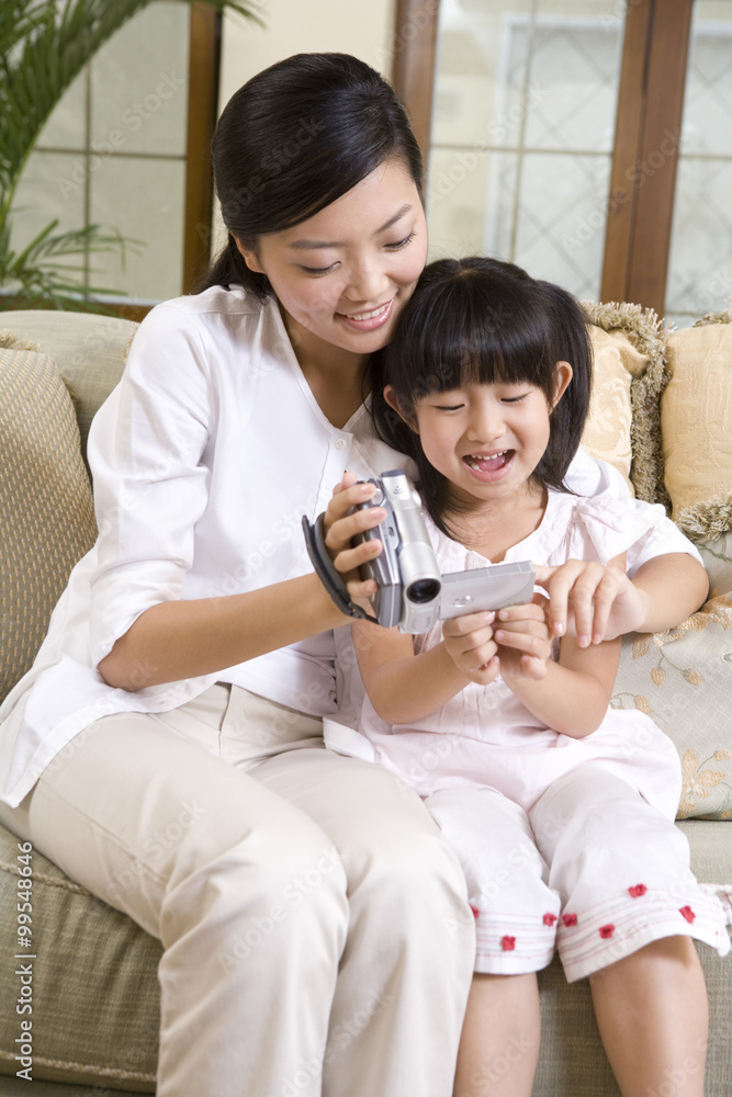 Mother and daughter using digital video camera