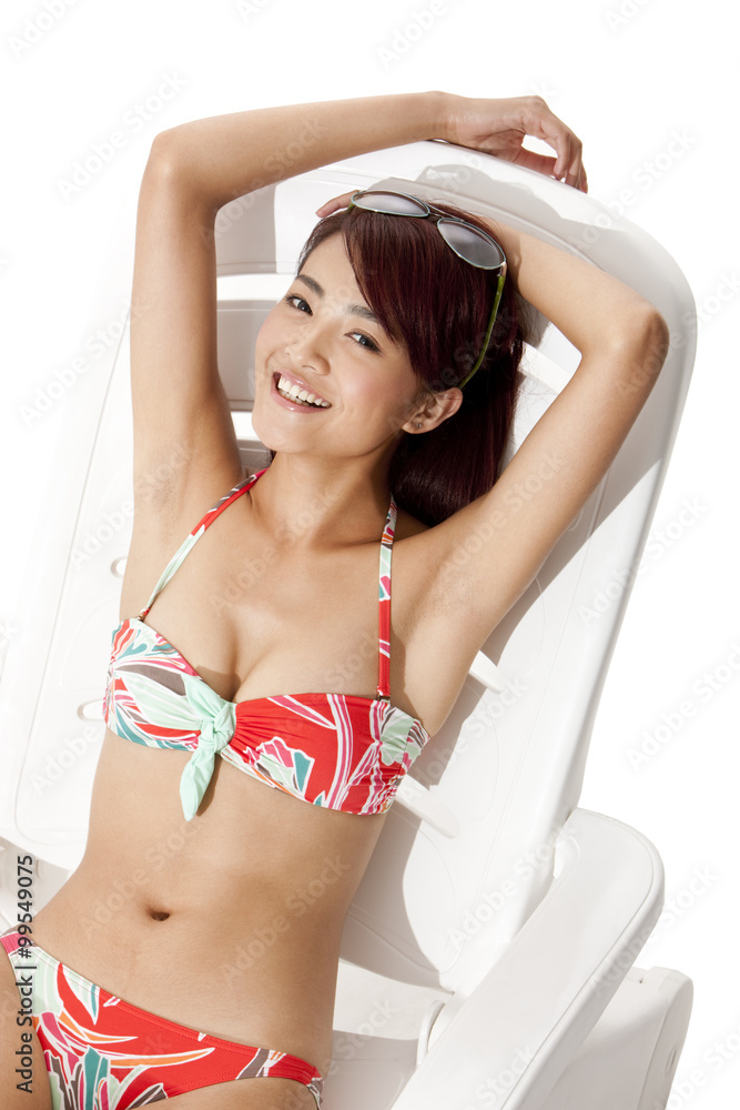 Young woman in bikini relaxing on sand chair