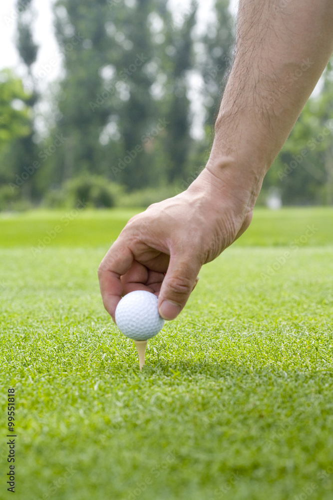 Close-up of putting a golf ball on tee