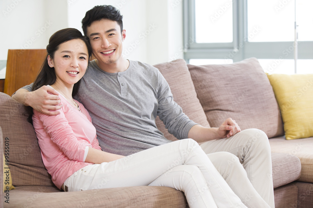 Happy young couple sitting on sofa