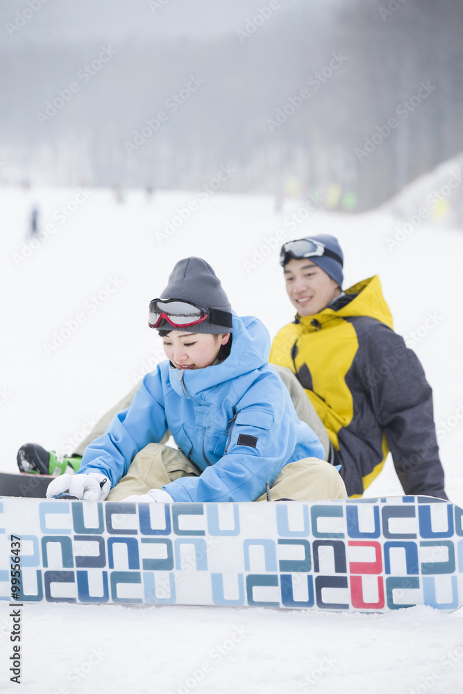 雪地上带滑雪板的年轻情侣