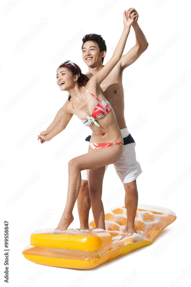 Young man and young woman in swimsuit having fun in air bed