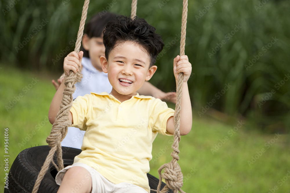 兴奋的男孩和小女孩在秋千上玩耍