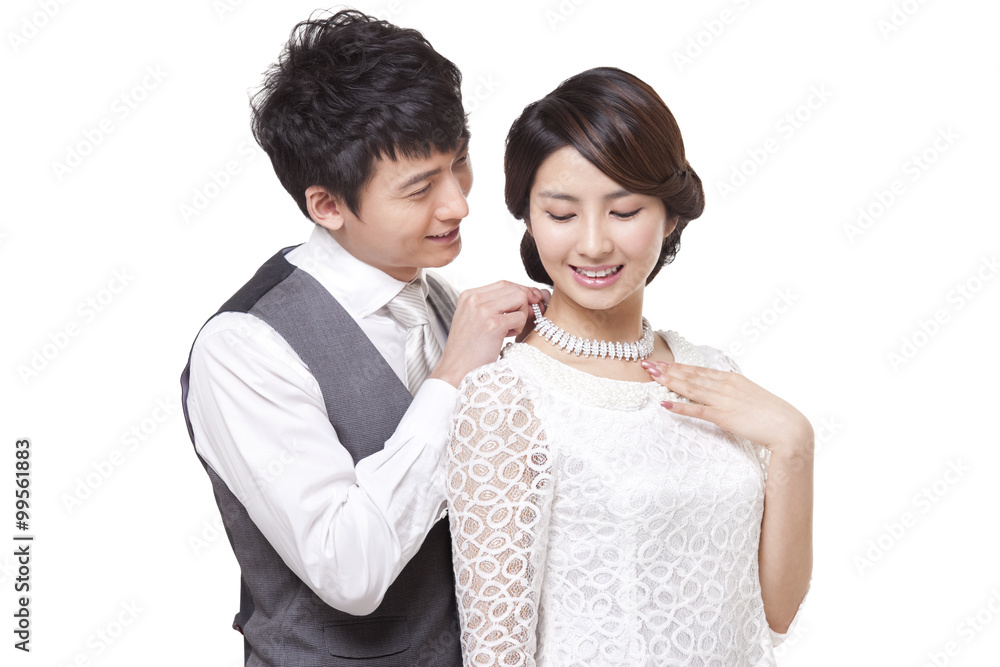 Happy young man fastening young womans diamond necklace