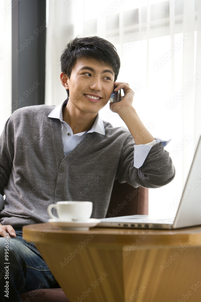 A young man talking on mobile phone at a coffee shop