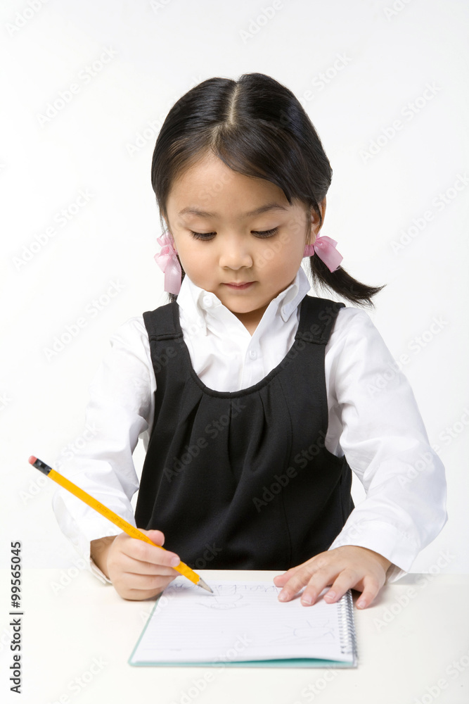 Little girl writes on a notebook