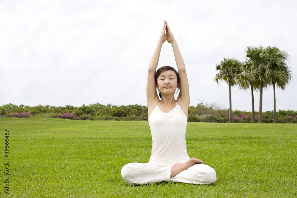 A woman practicing yoga on a grass field