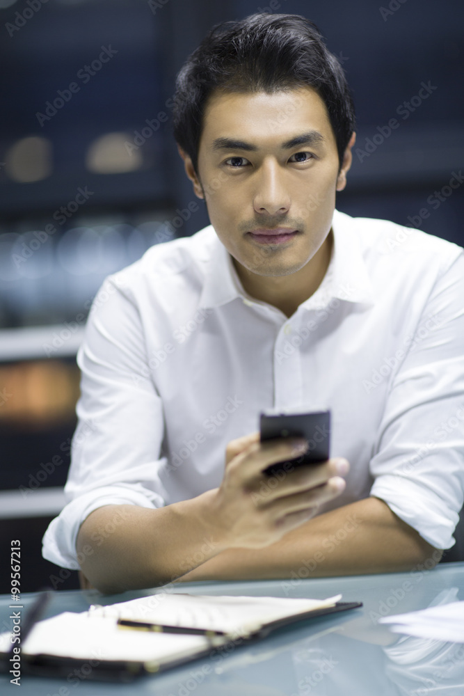 Young businessman using smart phone in office