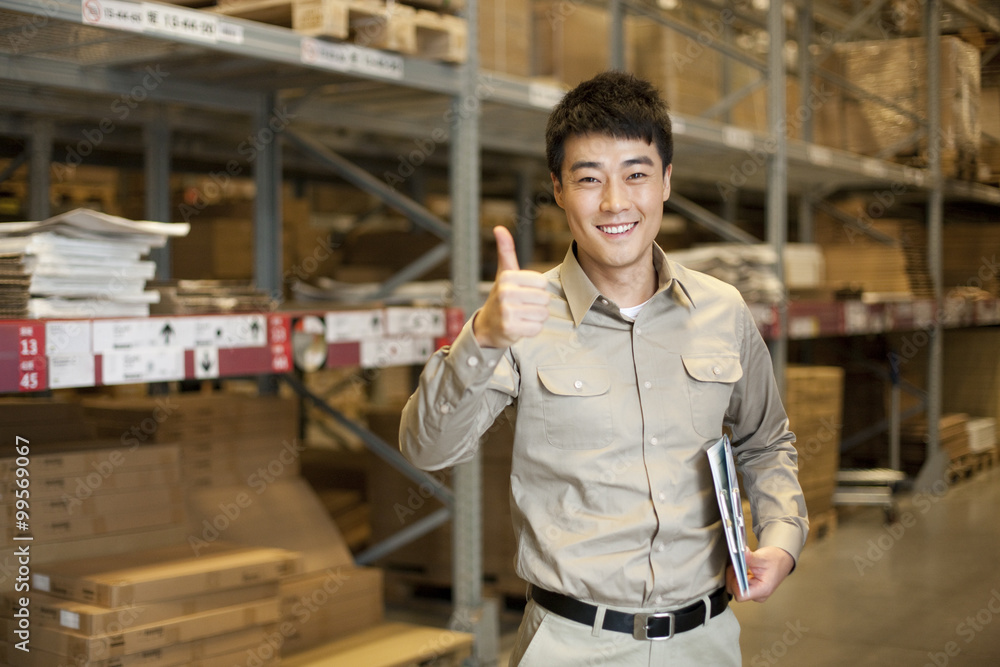 Male Chinese warehouse worker giving the thumbs up