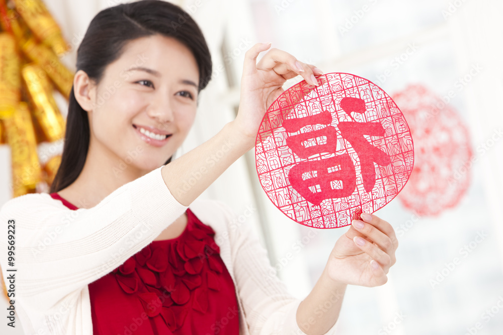 Young woman with Chinese New Year paper-cut for window decoration