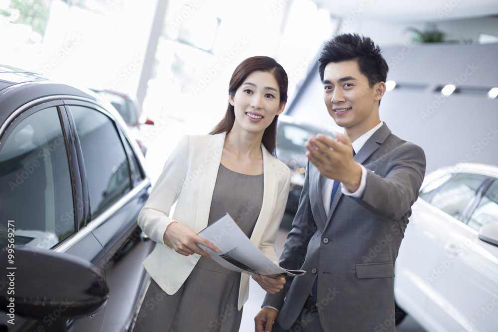 Young businesswoman choosing car in showroom