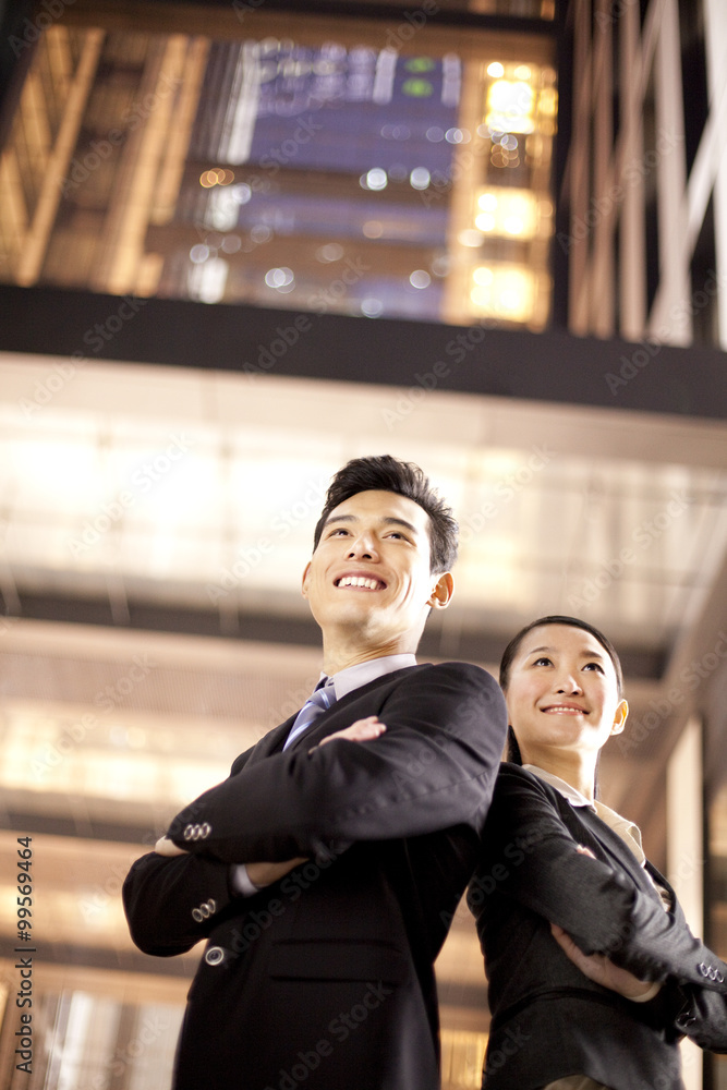 A businessman and businesswoman outside an office building at night