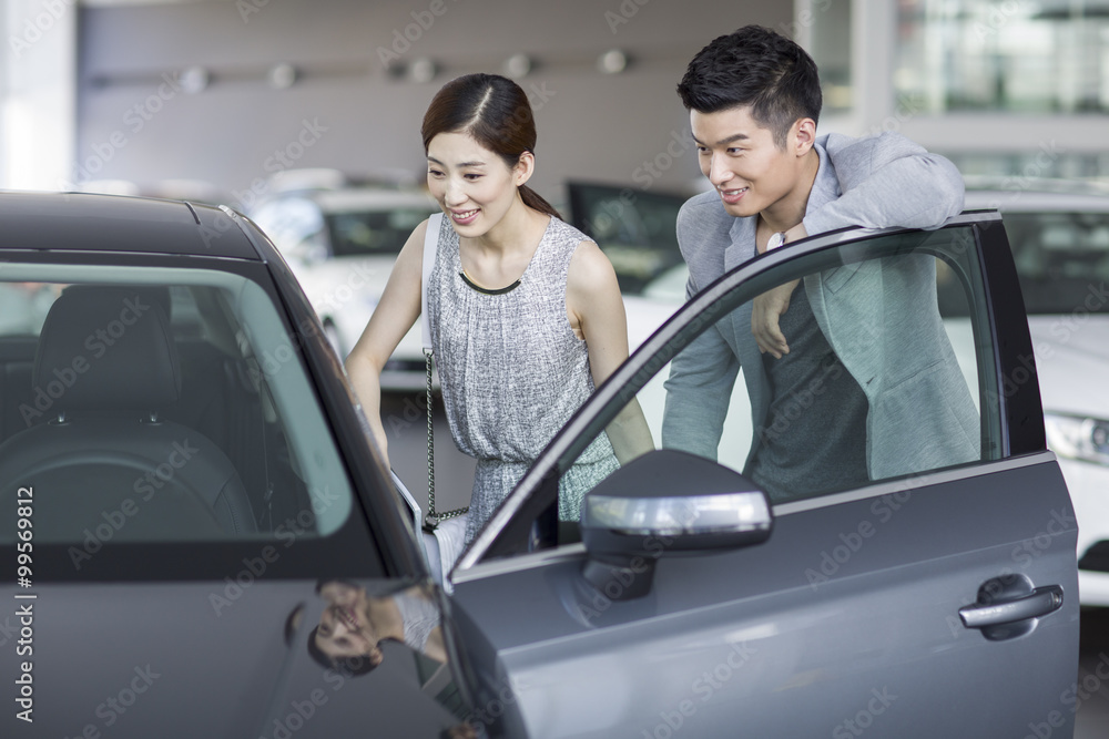 年轻夫妇在展厅里看新车