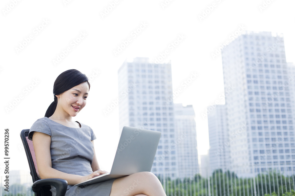 Young businesswoman working with laptop outdoors