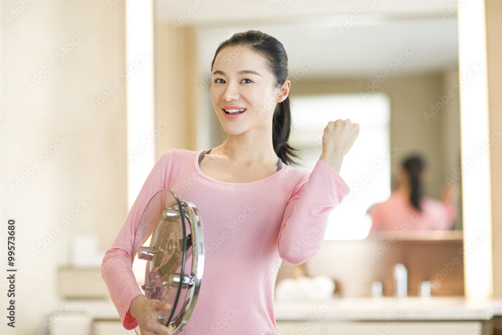 Happy young woman holding weight scale