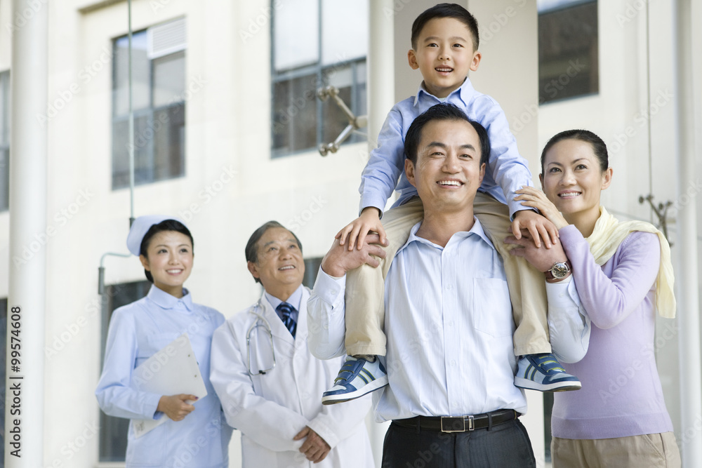 Young Family Stands in a Hospital Corridor With a Doctor and a Nurse